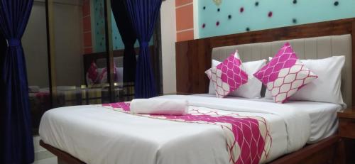 um quarto com uma cama com almofadas cor-de-rosa e brancas em HOTEL OM SAI em Vovale
