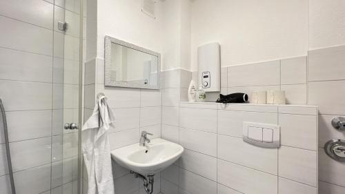 a white bathroom with a sink and a mirror at Apartments - an der Stadthalle in Neumünster