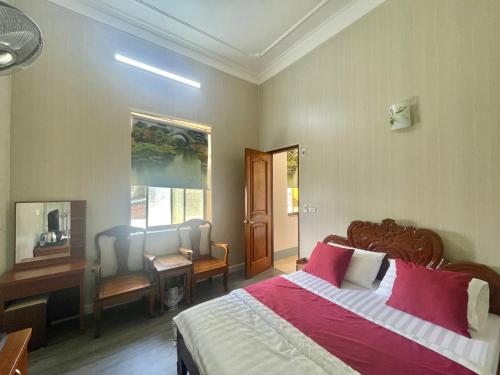 a bedroom with a bed and a desk and a window at Bach Dai Dung Hotel in Ha Tinh