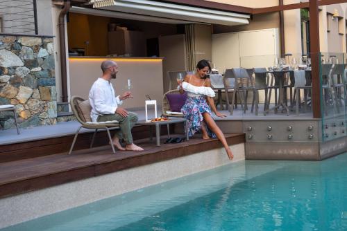 a man and a woman sitting next to a swimming pool at Hotel Zurigo in Varazze