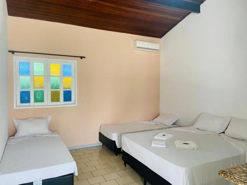 Cette chambre comprend 2 lits et une fenêtre. dans l'établissement Pousada Riviera, à Caraguatatuba