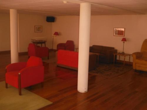 a living room with red chairs and a white pole at Hotel Alameda in Albergaria-a-Velha