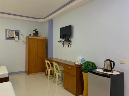 a room with a desk with a tv and chairs at Merangie Travellers Inn in Dauis