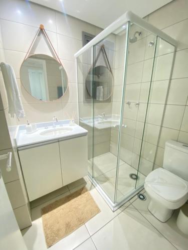 a bathroom with a glass shower and a toilet at TULUM Bertioga - belo apartamento com vista para o mar in Bertioga