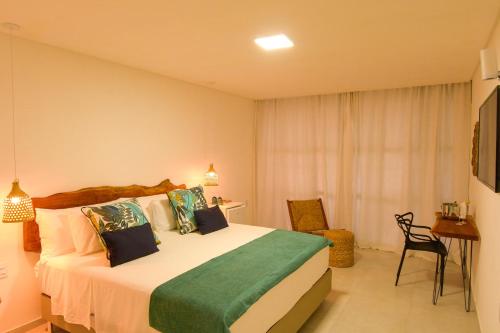 a bedroom with a bed and a table and a chair at Milie Lounge Pousada in Japaratinga