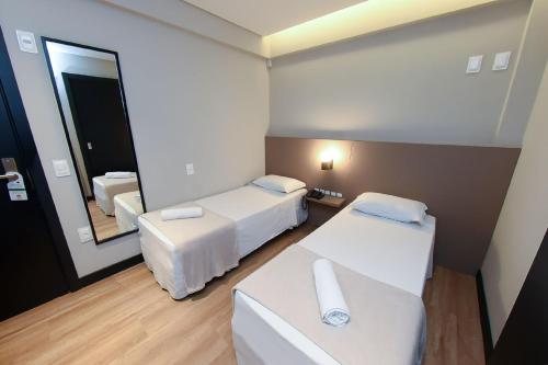 um quarto de hotel com duas camas e um espelho em Arco do Sol Park Hotel em Camboriú