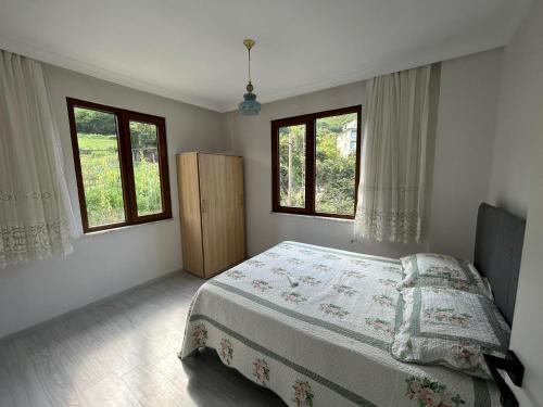 um quarto com uma cama e duas janelas em Yomra Villa Konaklama Günlük Kiralık em Yomra