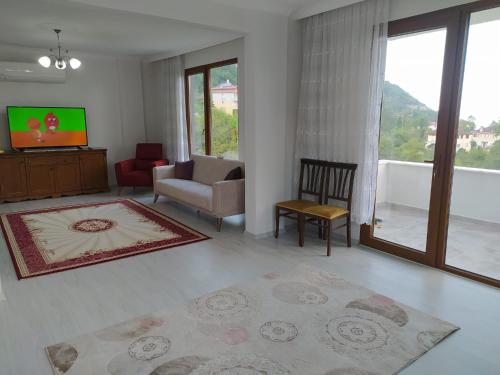 uma sala de estar com uma televisão, um sofá e uma cadeira em Yomra Villa Konaklama Günlük Kiralık em Yomra