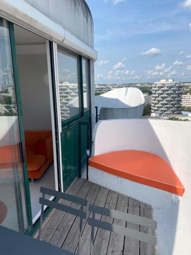 a balcony with a red bench on top of a building at 14eme et dernier étage - 3 pieces "Arty" de 65 m2 avec vue panoramique ! in Créteil