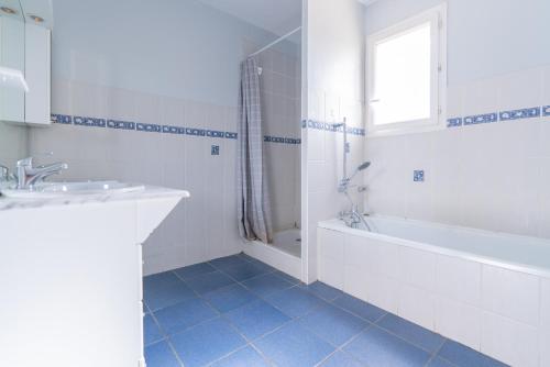 La salle de bains blanche est pourvue d'une baignoire et d'un lavabo. dans l'établissement Villa Tika, à Béziers