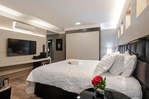 a bedroom with a bed with a television and flowers on a table at Full Jazz by Slaviero Hotéis in Curitiba