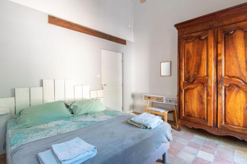 une chambre avec un lit et une armoire en bois dans l'établissement Au Coeur De L'Olivette - Climatisée avec piscine, à Aubais
