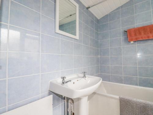 a blue tiled bathroom with a sink and a bath tub at 4 Greenbank Terrace in St Austell