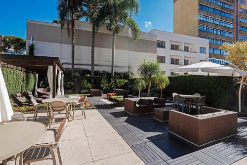 a patio with tables and chairs and a building at Full Jazz by Slaviero Hotéis in Curitiba