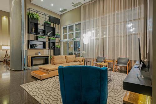 a living room with a couch and a table and a television at Full Jazz by Slaviero Hotéis in Curitiba