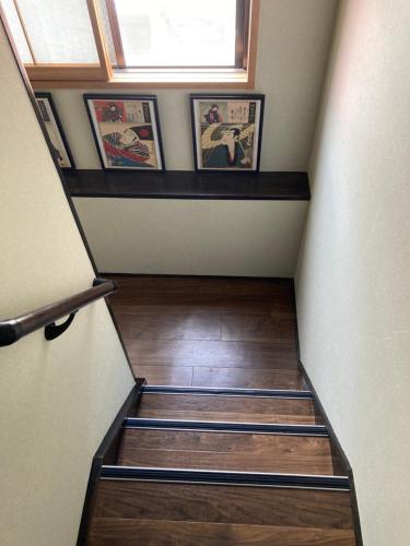 a set of stairs in a house with pictures on the wall at Lodging Tokyo Shibamata in Tokyo