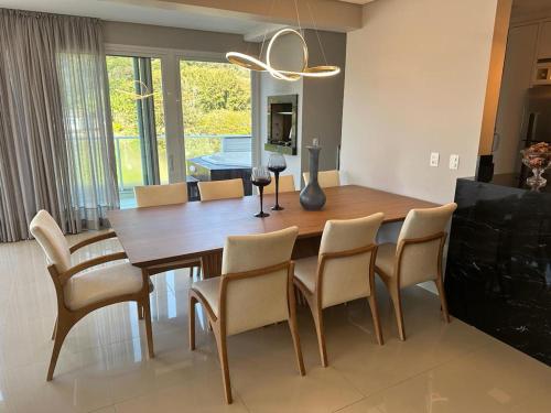 a dining room with a wooden table and chairs at Cobertura Duplex - La Belle Vue - Canajurê in Florianópolis