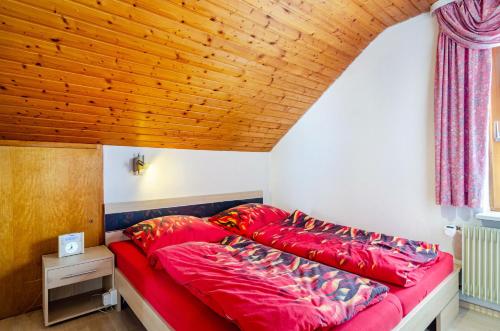 a red bed in a room with a wooden ceiling at Dachwohnung Schneider Bingen in Mengen