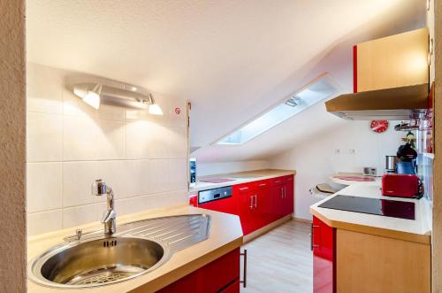 a kitchen with a sink and red cabinets at Dachwohnung Schneider Bingen in Mengen