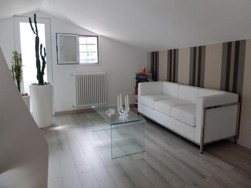 un soggiorno con divano bianco e tavolo in vetro di Casa Baroncelli a Siena