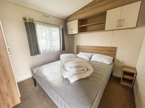 ein kleines Schlafzimmer mit einem Bett mit einer Decke darauf in der Unterkunft Superb 6 Berth Caravan At Martello Beach, Near Clacton-on-sea Ref 29008mc in Clacton-on-Sea