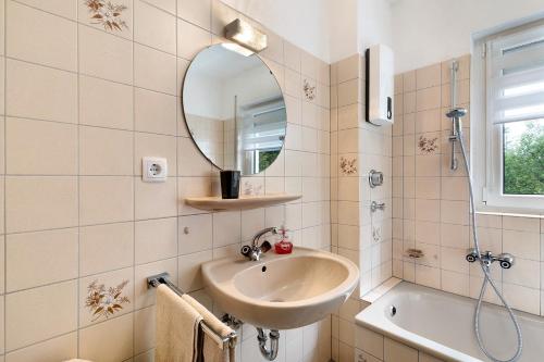 uma casa de banho com um lavatório, um espelho e uma banheira em Klug em Obertal