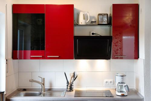 a kitchen with red cabinets and a sink at Klug in Schonach