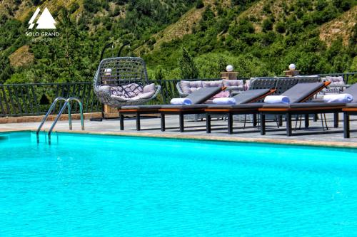 una piscina con mesas de salón y sillas junto a ella en Solo Grand Boshuri Hotel Wellness Resort 