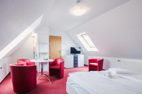 a bedroom with two beds and a table and red chairs at Pension Schwalbenhof in Klausdorf Mecklenburg Vorpommern