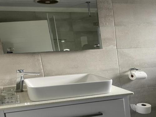 ein Badezimmer mit einem weißen Waschbecken und einem Spiegel in der Unterkunft Treklaer Lodge in Hartenbos