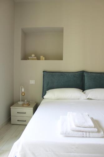 a white bed with a blue headboard and a night stand at Bene39 in Turin