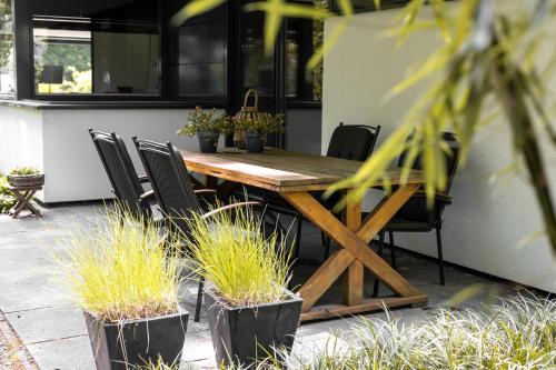 a wooden table and chairs on a patio with plants at Avellano in Helmond