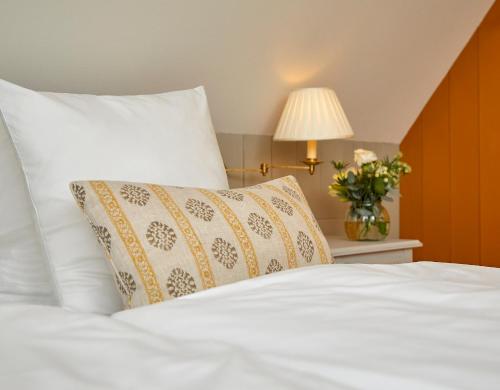a white bed with a pillow and a vase of flowers at Schackenborg Slotskro in Tønder