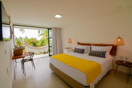 a bedroom with a bed with a yellow blanket at Milie Lounge Pousada in Japaratinga
