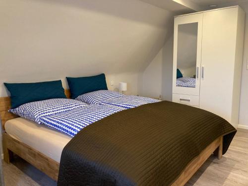 ein Schlafzimmer mit einem Bett mit blauen Kissen und einem Spiegel in der Unterkunft Kleine Auszeit, Schöne neue Ferienwohnung in Bitburg