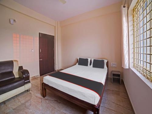 Un dormitorio con una cama grande y una ventana en OYO Hotel Rajaganga Lodge en Hassan