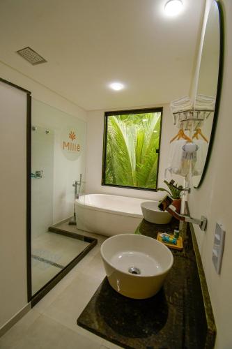 a bathroom with a sink and a bath tub at Milie Lounge Pousada in Japaratinga