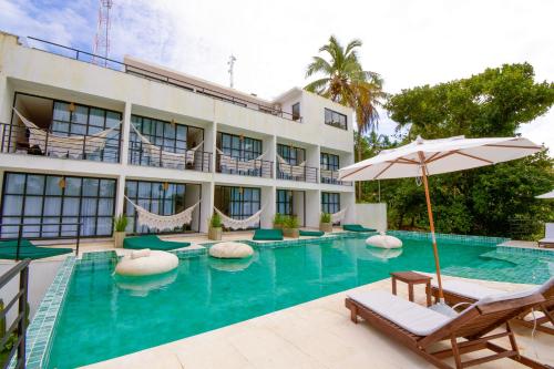 a hotel with a swimming pool with chairs and an umbrella at Milie Lounge Pousada in Japaratinga