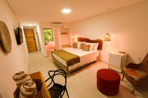 a bedroom with a bed and a chair and a table at Milie Lounge Pousada in Japaratinga