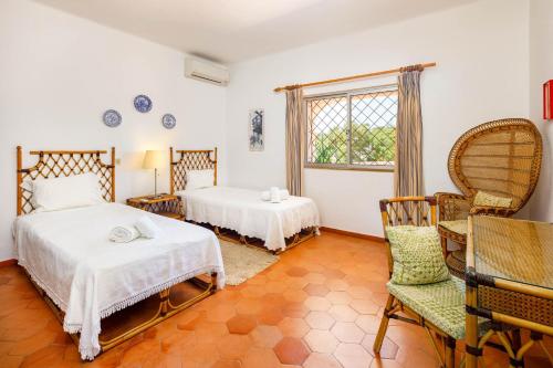 1 Schlafzimmer mit 2 Betten, einem Stuhl und einem Fenster in der Unterkunft Villa Vale Do Lobo 626 - 3 Bedroom villa - Great pool area - Perfect for families in Vale do Lobo