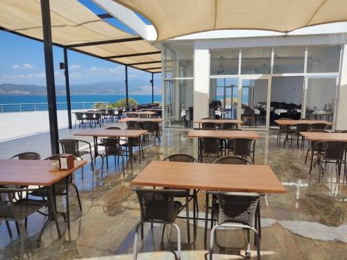 una cafetería vacía con mesas y sillas y el océano en Ni Marin Hotel, en Milas