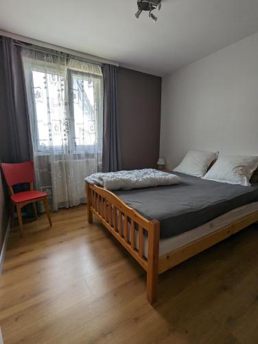 une chambre avec un grand lit et une chaise rouge dans l'établissement Gite 'chez Cocotte', à La Bresse