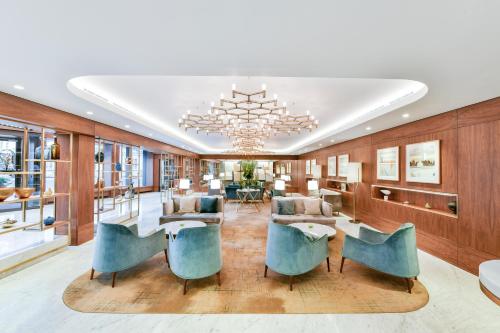 a lobby with blue chairs and a chandelier at Royal Lancaster London in London