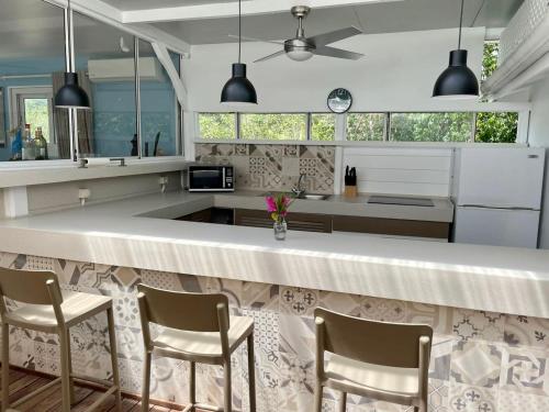 a kitchen with a bar with chairs and windows at Villa Branca - Les Terres Basses in Marigot