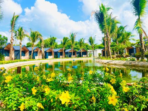 a resort swimming pool with palm trees and yellow flowers at Hồ Cốc Park & Resort in Xã Như Lâm