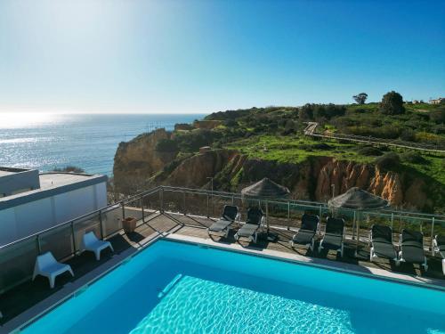 a swimming pool with chairs and a view of the ocean at Carvi Beach Hotel in Lagos