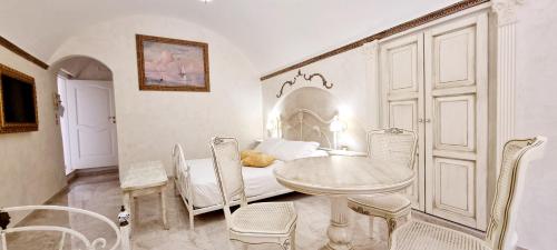 Camera bianca con tavolo, sedie e letto di Palazzo Castiglione a Gallipoli