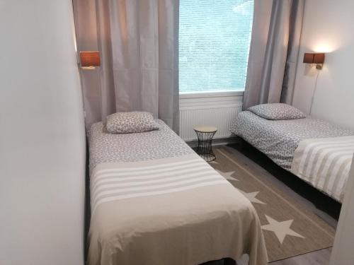 two beds in a small room with a window at Majoituspalvelu Nurmi Apartment Peipontie 3 B in Raahe