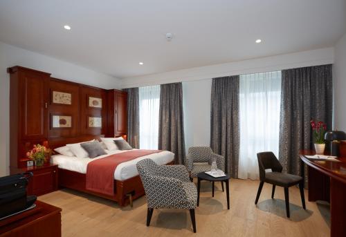 a hotel room with a bed and chairs and a television at Hotel Suisse in Geneva