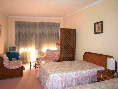 a hotel room with two beds and a chair at D. Carlos Residencial in Caldas da Rainha